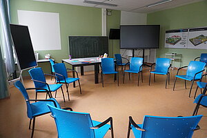 Im Klassenzimmer sind Stühle in einem Schulkreis aufgestellt. Gruppen können sich das Mobiliar nach ihrem Bedarf aufstellen.