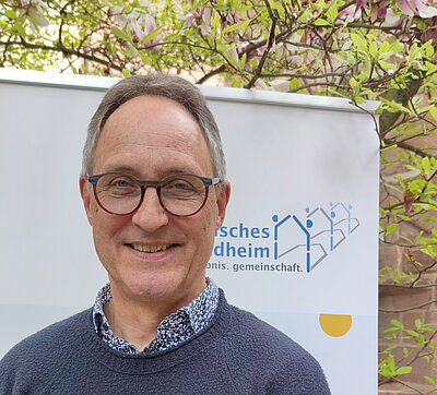 Mann mit Brille vor Banner Bayerisches Schullandheimwerk