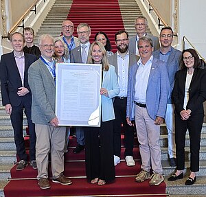 Auf eine Treppe im Bayerischen Landtag stehen die Staatsministerin Anna Stolz und Vertreterinnen und Vertreter des Runden Tisches