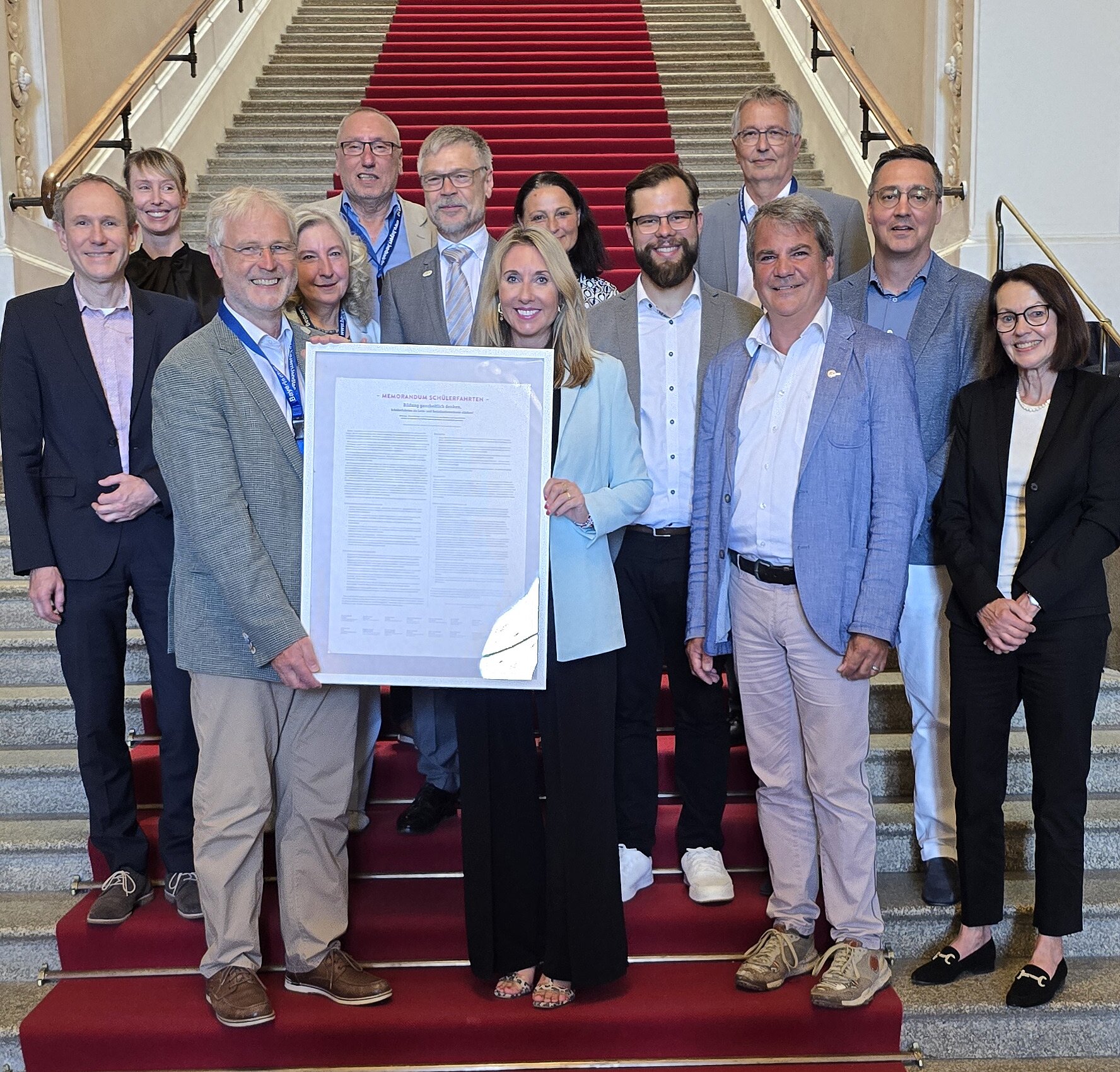 Auf eine Treppe im Bayerischen Landtag stehen die Staatsministerin Anna Stolz und Vertreterinnen und Vertreter des Runden Tisches