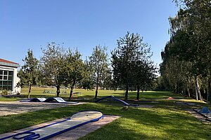 Die Minigolfanlage des Schullandheims im Außengelände umrandet von kleinen Bäumen.