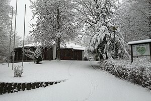 Schneebedecktes Parkgelände und ein rund gebautes Haus