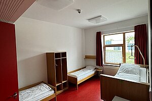 Ein Zimmer mit zwei Betten und einem Pflegebett.