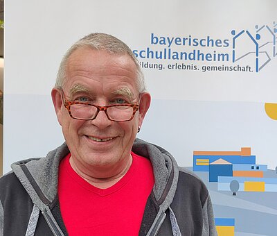 Mann mit halber Brille und rotem T-Shirt 