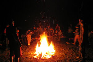 Lagerfeuer und die Kinder und Jugendlichen im Kreis darum. Ein beliebtes Abendprogramm im Schullandheim. 