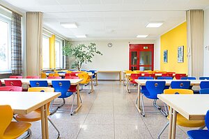 Im Speisesaal stehen bunte Stühle an den Tischen. Der Raum ist teilbar in zwei kleinere Räume.