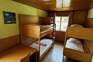 Mehrbettzimmer mit zwei Stockbetten. und einem Tisch mit Stuhl.