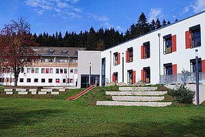 Blick auf das Schullandheim von der Gartenseite aus. Links hinten ist der Altbau zu sehen, auf der rechten Seite der zweistöckige Neubau mit Flachdach. 
