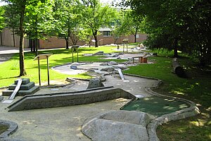 Auf dem Gelände des Schullandheims befindet sich eine Minigolfanlage, die auf dem Bild im Schatten liegt.