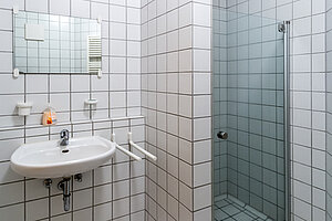 Blick in eine Nasszelle, mit Waschbecken und Dusche.